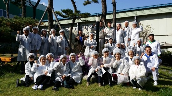 진천공장에 초대한 북향민과 함께 단체 사진을 찍은 J형