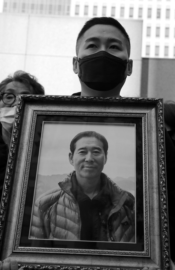 지난 10월 27일 부산고등법원 앞에서 있었던 "고 정순규 님 2주기 추모 기자회견"에서 정석채 씨가 아버지의 사진을 들고 서 있다. ©장영식