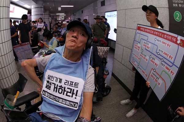 2018년 8월 지하철역에서 장애인 휠체어 리프트 추락 사건이 발생한 뒤, 장애인 활동가들이 사과와 지하철역 엘리베이터 설치를 요구하며 시위하고 있다. 김진수 선임기자.  출처: 한겨레21,  2021-12-02.