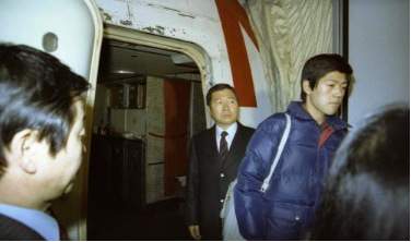 1982년 12월23일 김대중과 이희호는 아들 홍업·홍걸과 함께 미국 망명길에 올랐다. 서울대병원 뒷마당에서 구급차에 실려 김포공항에 도착한 가족은 애초 예약한 대한항공이 아닌 미국적 노스웨스트항공에 몰래 태워졌다. 취재진과 환송객을 따돌리기 위한 ‘비밀 추방 작전’이었다. 12월23일 저녁 김포공항에 대기 중인 노스웨스트 항공기 트랩 앞에 도착한 앰뷸런스에서 내린 김대중(왼쪽)과 막내아들 홍걸(오른쪽)의 모습. 사진 김대중평화센터 제공(사진출처 : https://www.hani.co.kr/arti/PRINT/734711.html)