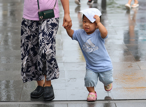 소나기가 내리는 날, 한 어린이가 종이로 비를 피하며 길을 지나고 있다. 출처 =한겨레신문 기사 (8/28 사회면)