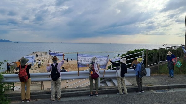 해변에 도착한 후 시민들을 향해 도보행진단의 플래카드를 들고 홍보하고 있는 동지들.