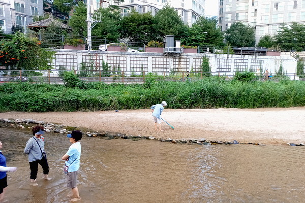▲ 수중 마사지를 즐기는 아주머니들 뒤로 묵묵히 모래를 고르는 할머님(출처 : 김미경) 