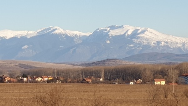 불가리아 땅을 상징하듯 산과 마을과 평지가 한 눈에 담긴 장면.