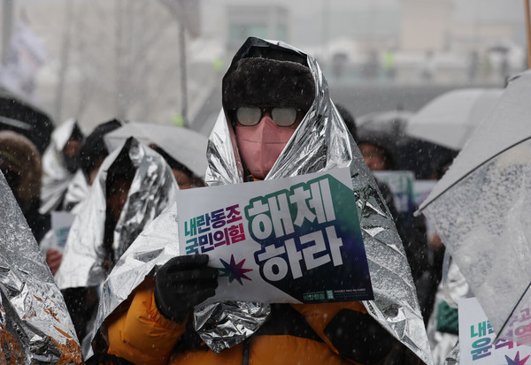 서울 전 지역에 대설주의보가 내려진 5일 오전 서울 용산구 관저 인근 ‘노동자 시민 윤석열 체포대회’ 농성장에서 열린 기자회견에서 안경에 김이 서린 한 시민이 손팻말을 들고 있다. (글 사진 한겨레신문 김혜윤 기자 unique@hani.co.kr)