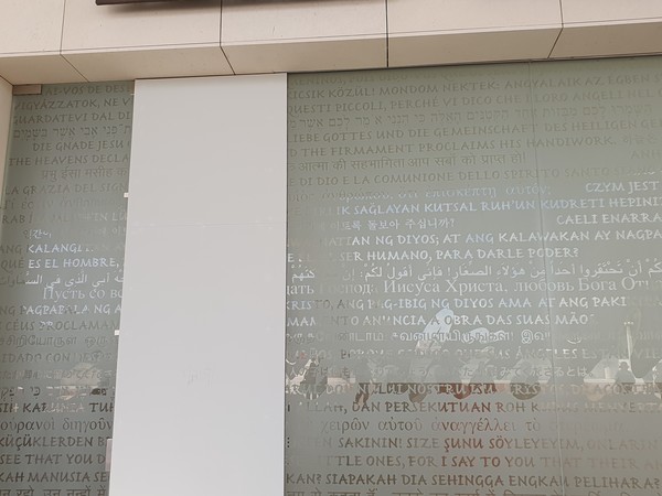 사진 김인수 / 삼위일체 성당 입구 반투명 유리창에 ‘한글로 새겨진’ 시편 8장 5절과 시편 19장 2절 , 묵주기도 모후 대성당, 성모 발현 경당, 예수 죽음 경당, 삼위일체 대성당, 그리고 녹색 단체 조끼의 유용함.