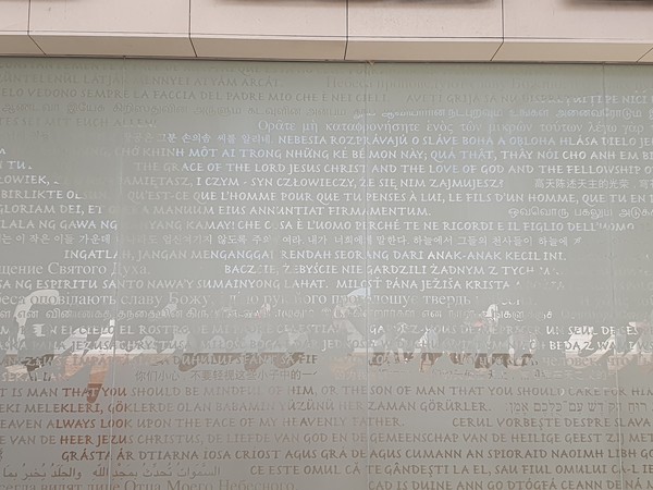 사진 김인수 / 삼위일체 성당 입구 반투명 유리창에 ‘한글로 새겨진’ 시편 8장 5절과 시편 19장 2절 , 묵주기도 모후 대성당, 성모 발현 경당, 예수 죽음 경당, 삼위일체 대성당, 그리고 녹색 단체 조끼의 유용함.