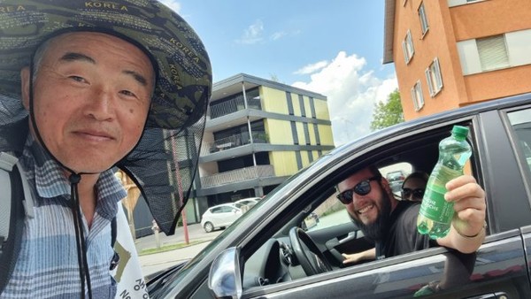 차를 세우고 시원한 음료수를 건네는 운전자와 셀피~