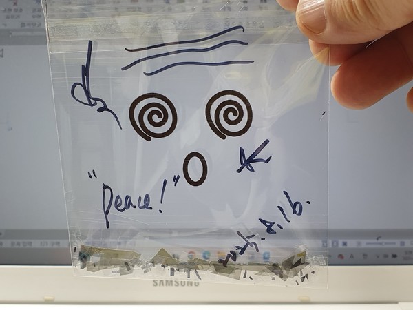 사진 김인수 / 2025년 오사카과학축제 빛튐 실험 3실험원리 “두 편광필름(손전화, 노트북 등) 사이에 복굴절 하는 물질(방해석, OPP 등)이 있을 때 광탄성(빛튐)이 나타난다.”를,‘기본도안이 그려진 OPP 봉지 속에 편광필름 조각을 가위로 자유롭게 잘라 넣은 후, 노트북(손전화) 화면 앞에서 봄’으로써 빛튐 아트 완성.