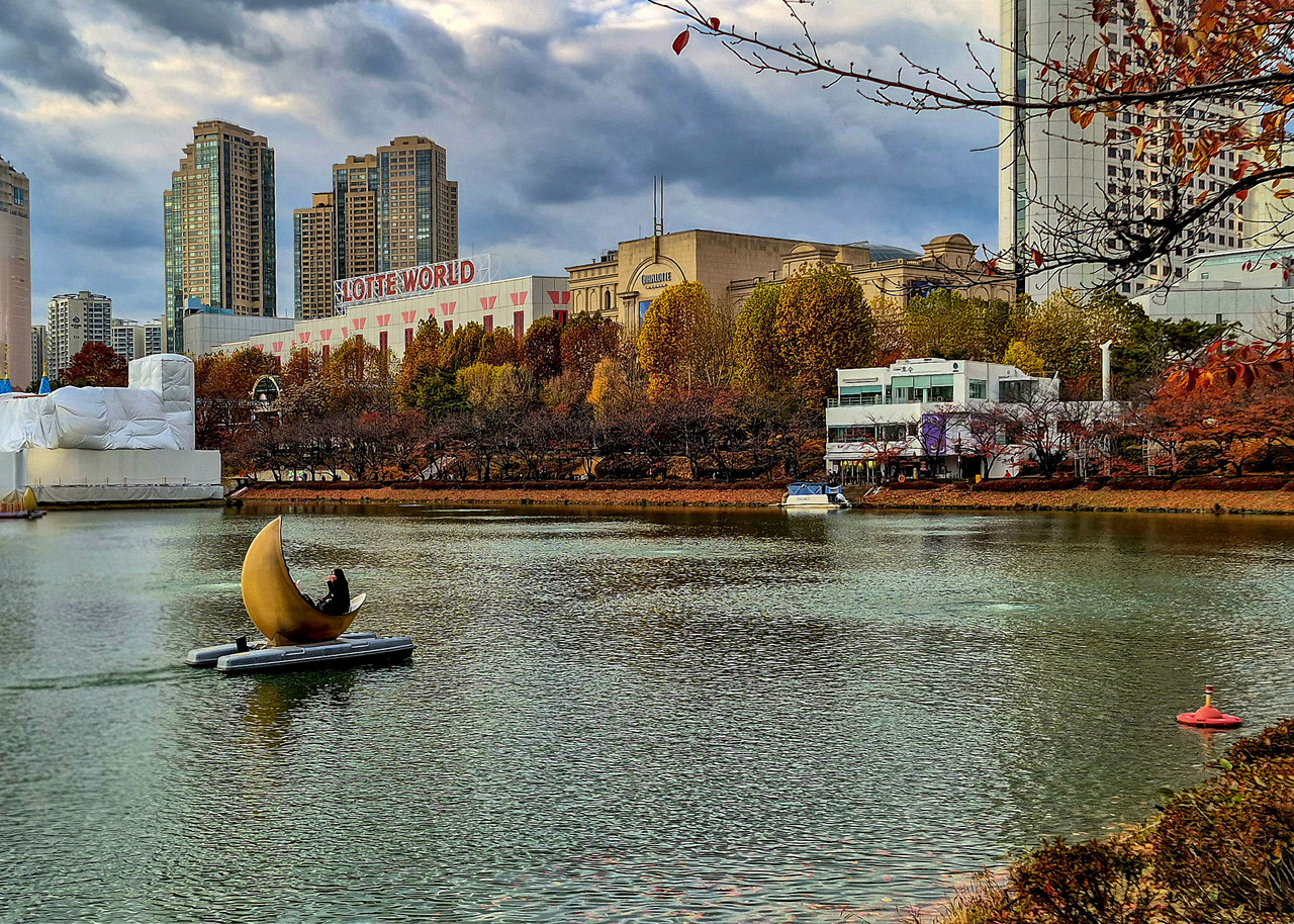 석촌호수에서 늦가을의 속삭임을 듣고,  태양이 오늘을 마감하는 빛을 만났다.   소녀가 안녕하는 뒷모습과 함께. 2025.11.22.